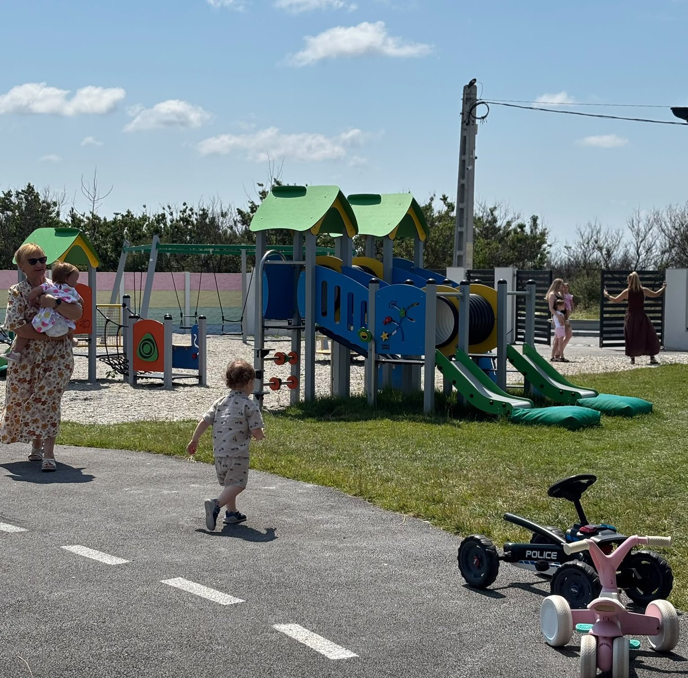 Curtea grădiniței Atelier de Bucurie, cu locul de joacă și cer senin